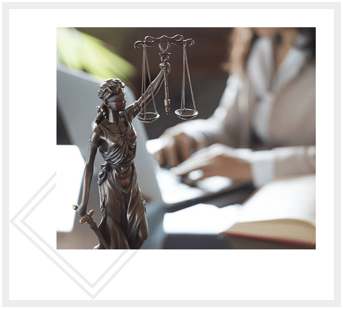 A statue of lady justice and a person at a desk.